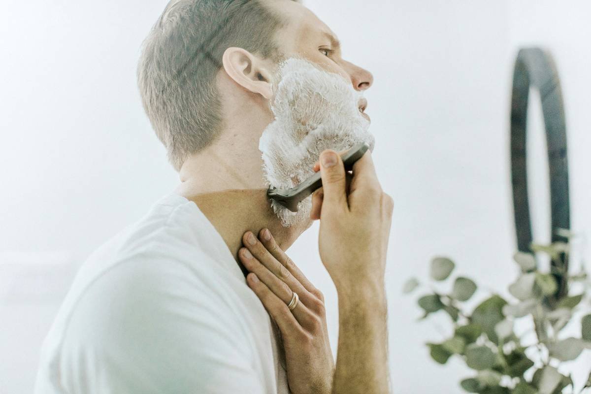 A close-up image of flexible hold beard balm jar next to a wooden comb