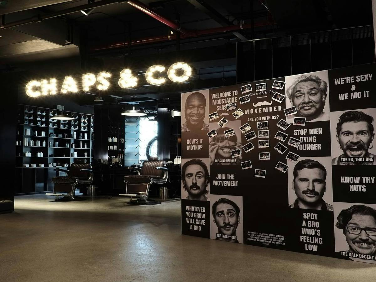 A man applying beard balm with his fingers while holding a brush nearby.