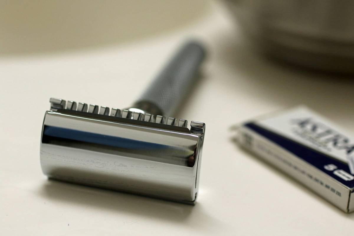 A close-up of beard balms and grooming tools next to a styled beard.