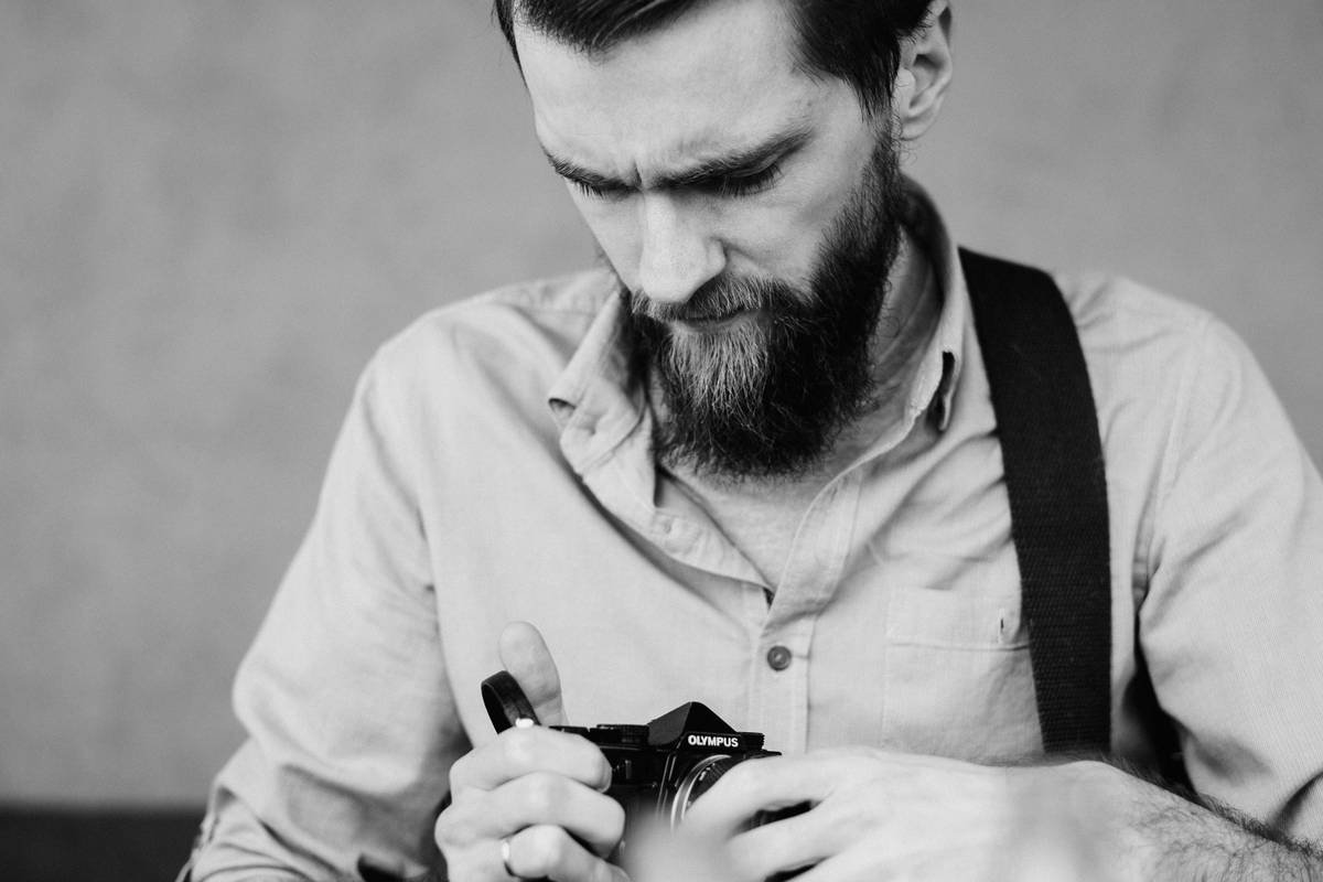 A worried man holding a analog Olympus camera
