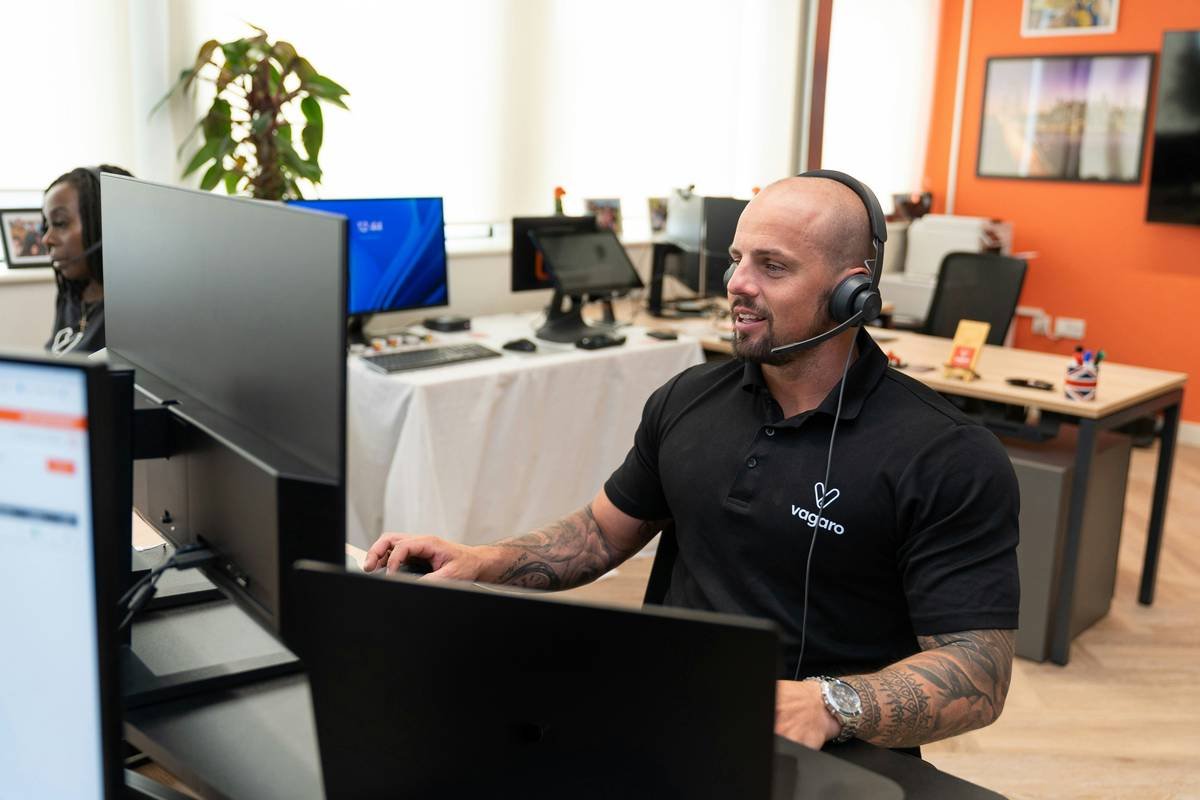 A customer support representative at Vagaro is assisting a client through a headset, offering support in an office.