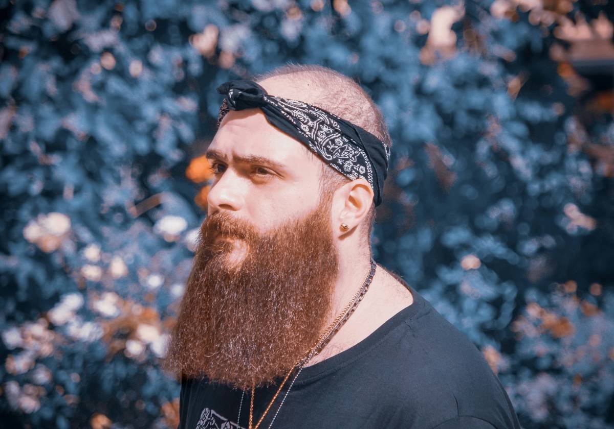 Close-up of beard grooming comb gliding through thick beard hair showing even distribution of beard balm