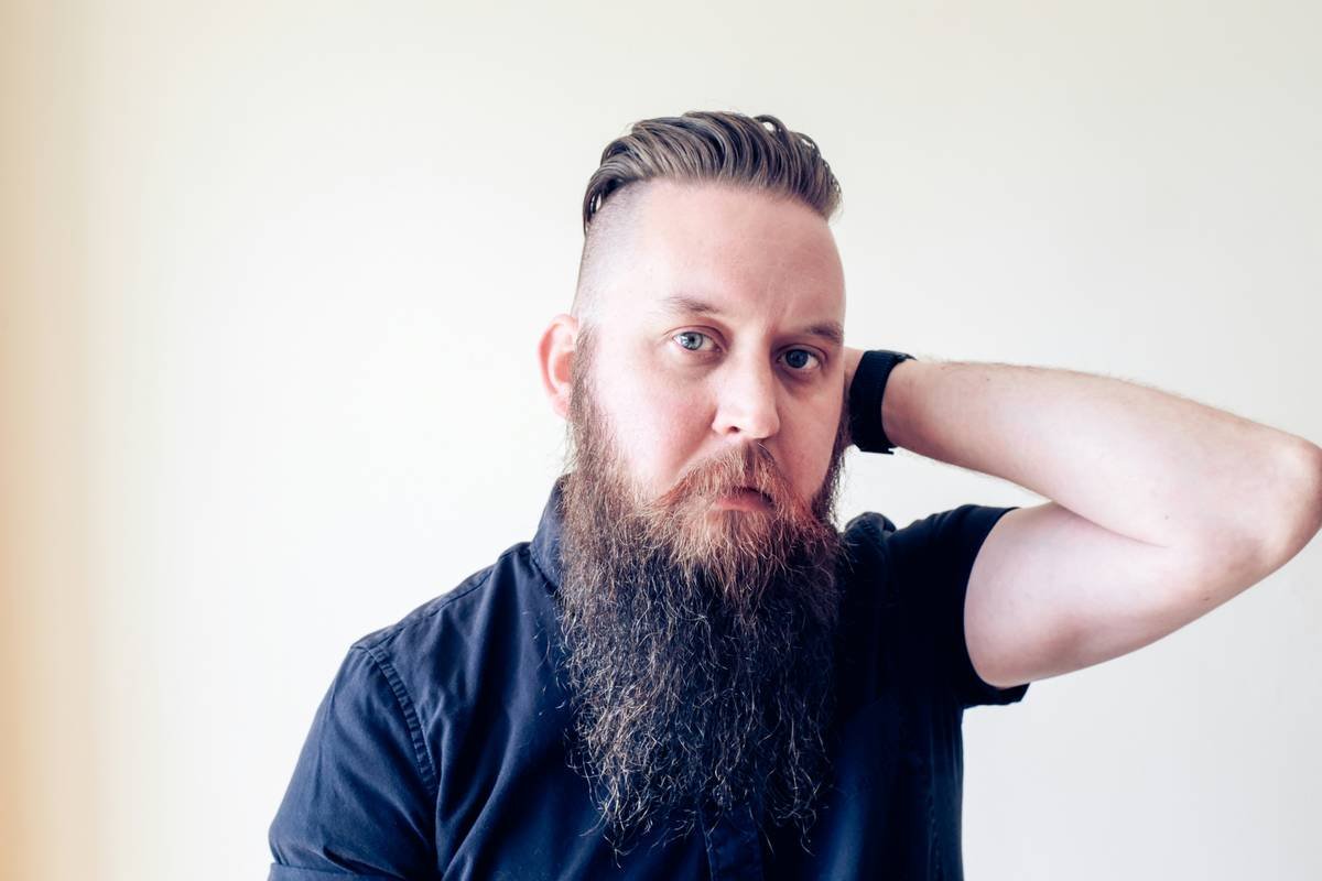 Man using a precision beard balm applicator to apply product directly to skin under beard