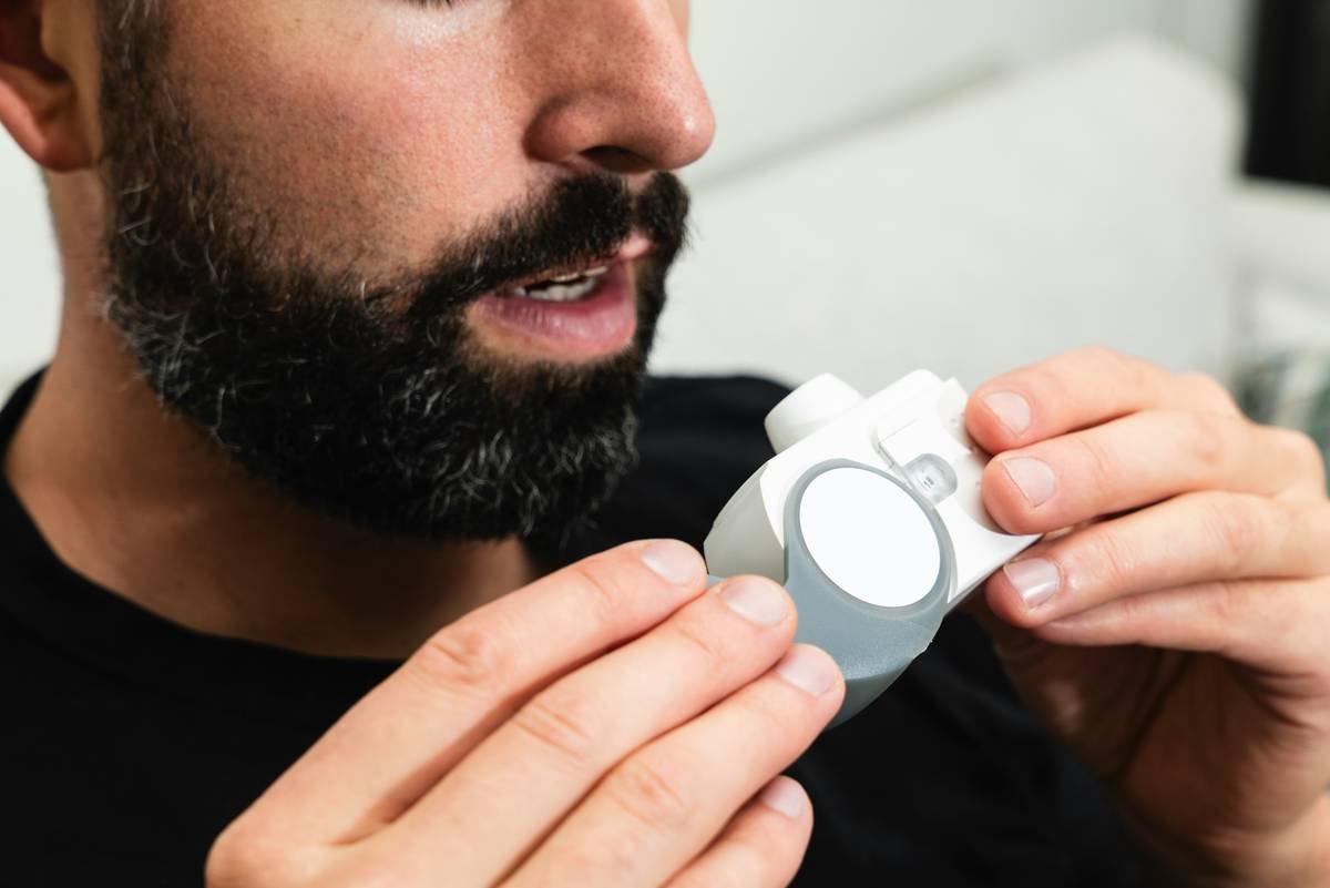 Close-up of stainless steel beard balm applicator beside open tin of balm