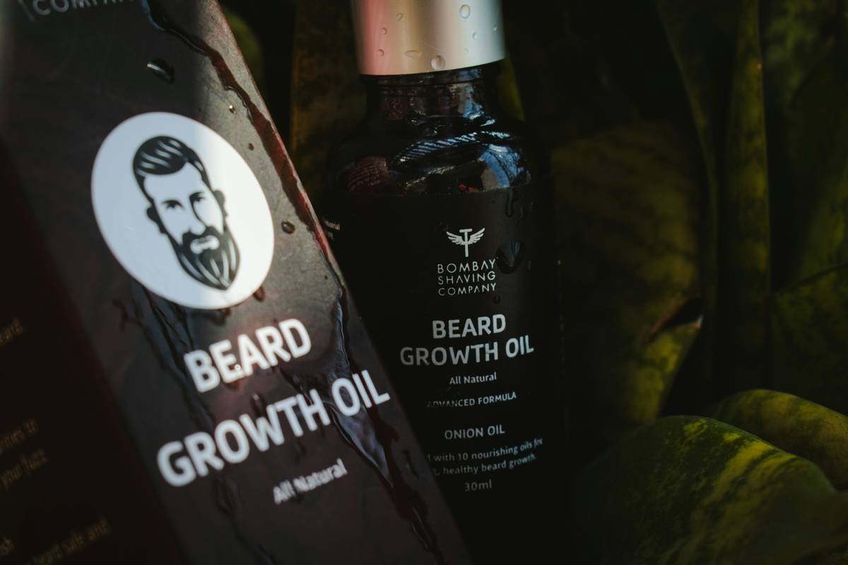 Hand applying beard styling mousse to damp facial hair for natural hold and definition