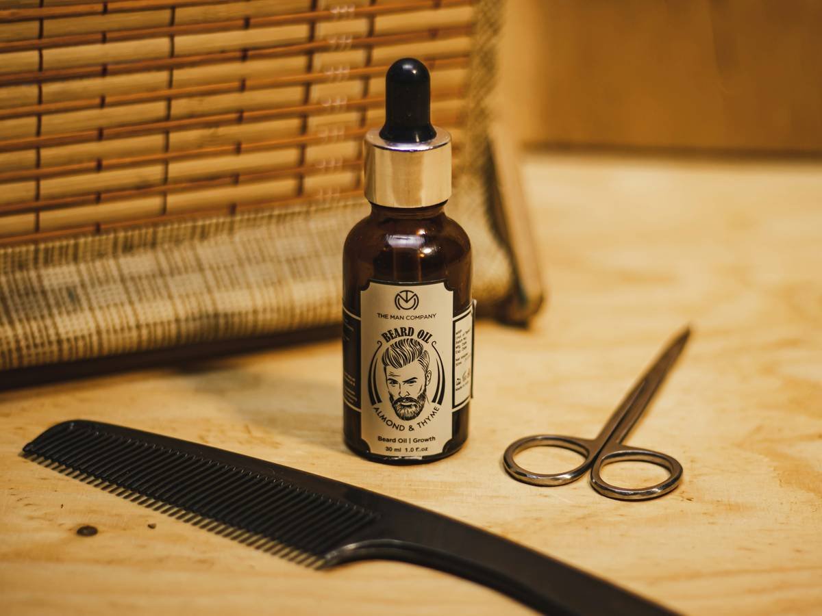 Hand applying beard balm with jojoba oil to a thick, dark beard for hydration and styling